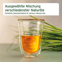 Glas mit einer ausgewählten Mischung verschiedener Naturöle. Das Bild zeigt das Öl in einem transparenten Glas, umgeben von frischen grünen Grashalmen.