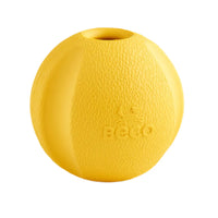 Ein Beco Fetch Ball aus Naturkautschuk in der Hand eines Hundebesitzers, der ihn für ein Wurfspiel im Freien vorbereitet. Der Ball ist elastisch, robust und mit einem angenehmen Vanilleduft versehen, um den Hund zum Apportieren zu motivieren.