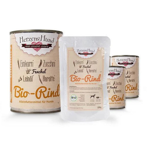 Verschiedene Verpackungen von HerzensHund Bio-Rind, einem Alleinfutter für Hunde. Die Produkte beinhalten Zutaten wie Einkorn, Zucchini, Fenchel, Leinsamen und Karotten. Die Verpackungen sind in Dosen und Beuteln erhältlich.